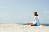 Woman practicing yoga at sandy beach, List, Sylt, Schleswig-Holstein, Germany