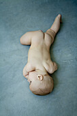 Nude baby lying on stomach on the ground, full length, high angle view