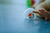 Baby playing with rubber duck on the ground, cropped view of hand