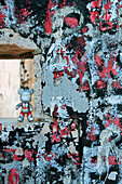 Plastic bear figurine standing in hole in graffitied wall