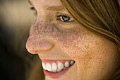 Young woman with freckles smiling, profile