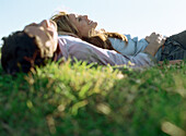 Young couple lying together in grass, smiling