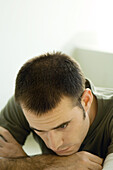 Man resting head on arm, looking down