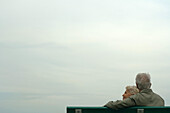 Senior couple sitting together on bench, rear view