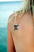 Roman numeral two tattooed on woman's shoulder