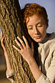 Woman embracing tree, eyes closed