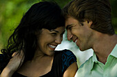 Young couple smiling at each other outdoors, close-up