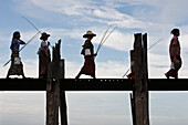 Amarapura, Myanmar, women with fishing rods and buckets walking across U Bein Bridge