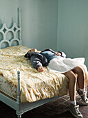 Woman lying on back, legs hanging off edge of bed