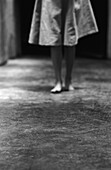 Woman standing barefoot on concrete, lower section, b&w