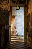 Woman riding scooter on hardwood floor, seen through doorway, blurred motion