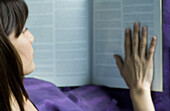 Woman reading reference book, high angle view, cropped