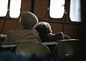 Elderly couple sitting inside ferry, rear view