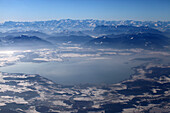 Aerial shot of northern lake Chiemsee in winter, Chiemgau Alps in background, Bavaria, Germany