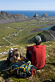 Norway, Lofoten Islands, trekkers admiring the city of Vaeroy