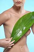 Young woman holding an aspidistra leaf on her chest