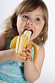 Little girl eating banana, studio