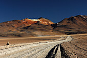 Chile, Laguna Colorada district, trail in desert, mountains in the back