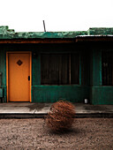 Rundown Motel With Tumbleweed in Front of Door