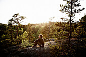 Woman Sitting on Large Rock in Forest Clearing, Sweden