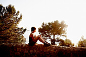 Woman Sitting on Rock Wall and Looking at Mediterranean Sea, Mallorca, Spain