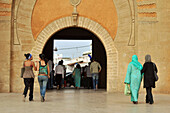 Moroccan women dressed in modern clothes and traditional clothes in front of the gate to medina, Rabat, Morocco