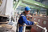 Worker painting railing, cruiser under construction in dry dock, Meyer Werft, Papenburg, Lower Saxony, Germany