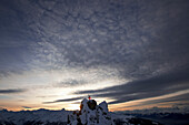 Skifahrerin steht auf einem Berggipfel in der Abenddämmerung, Chandolin, Anniviers, Wallis, Schweiz