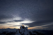 Zwei Skifahrer stehen auf einem Berggipfel in der Abenddämmerung, Chandolin, Anniviers, Wallis, Schweiz