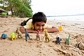 Thailändischer Junge am Strand mit seinen Dinos, Khao Lak, Andamanensee, Thailand