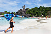 Boy carrying umbrella on to the fine white sandy beach at Sail Rock, Similan Islands, Andaman Sea, Thailand