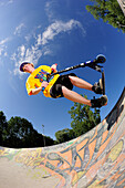 Young man performing jump with scooter, skatepark, Munich, Upper Bavaria, Germany