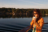 Frau mit Tasse Kaffee an Bord von Kreuzfahrtschiff MS Astor, Transocean Kreuzfahrten, während einer Kreuzfahrt durch die Ostsee, Stockholmer Schären, nahe Stockholm, Schweden, Europa, MR