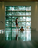 Couple at indoor pool looking out of a picture window, Vigiljoch, Lana, Trentino-Alto Adige/Suedtirol, Italy