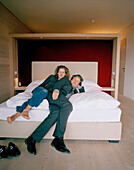 Paar sitzt auf einem Bett im Hotelzimmer, Vigilius Mountain Resort, Vigiljoch, Lana, Trentino-Südtirol, Italien