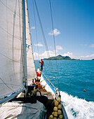 Sailor on transport sailer La Belle Praslinoise on its way to Praslin, ahead St. Anne Island Marine National Park, La Digue and Inner Islands, Republic of Seychelles, Indian Ocean