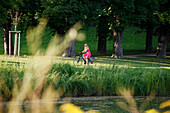 Woman cycling through the castle gardens on an e-bike, bike tour, Lower Castle Gardens, Stuttgart, Baden-Wurttemberg, Germany