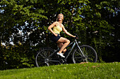 Woman biking through the castle gardens on an E-Bike, bike tour, e-bike, Lower Castle Garden, Stuttgart, Baden-Wurttemberg, Germany