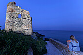 Eine Frau sitzt vor dem Genuesischen Turm, Erbalunga, Cap Course, Korsika, Frankreich