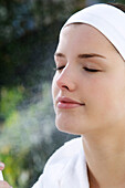 Woman spraying water on her face, inside