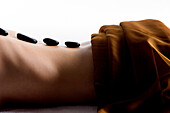 Nackte Frau, liegend, mit Peebles im Rücken, brauner Textilstoff auf dem Gesäß, Nahaufnahme
