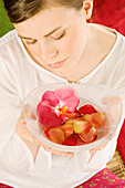 Young woman holding flower petals in a little dish, view from above