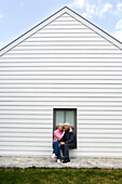 Senior couple embracing, sitting on a window sill