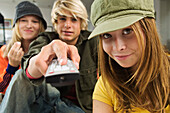 2 teenage girls and teenage boy using remote control