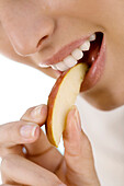 Portrait of a young woman eating a piece of apple, indoors