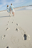 Couple walking on the beach, rear view