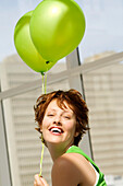 Portrait of young woman holding green balloons