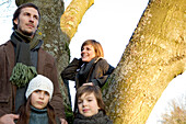 Two children standing near a tree with their parents