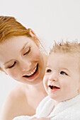 Close-up of a young woman wrapping her son in a towel and smiling