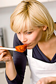 Close-up of a young woman smelling tomato sauce